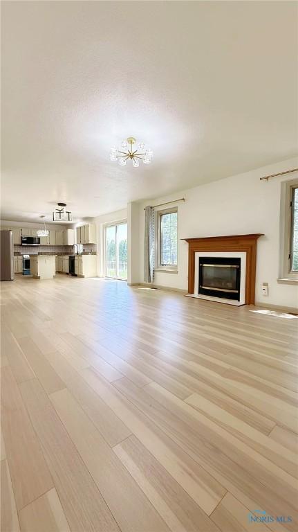 1303 Finch Dr, Bowling Green, OH 43402 - unfurnished living room with light wood-style floors and a glass covered fireplace