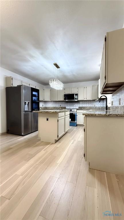 1303 Finch Dr, Bowling Green, OH 43402 - kitchen with appliances with stainless steel finishes, tasteful backsplash, light wood-style floors, light stone counters, and decorative light fixtures