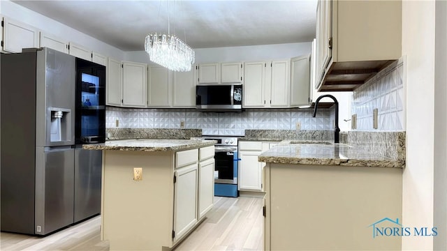 1303 Finch Dr, Bowling Green, OH 43402 - kitchen featuring appliances with stainless steel finishes, light stone counters, a chandelier, and decorative backsplash