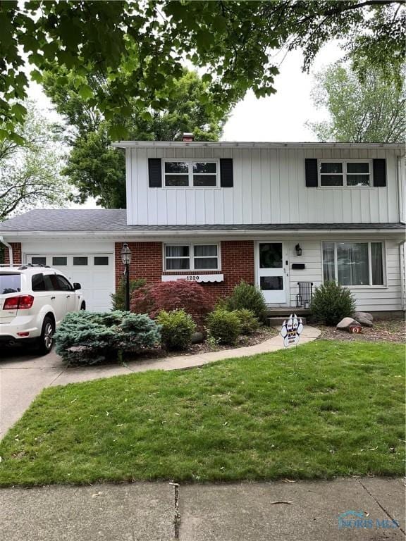 1220 Birch Ave, Maumee, OH 43537 - view of front of home featuring a garage, a front yard, driveway, board and batten siding, and brick siding