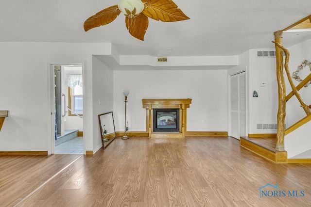 3133 126th St, Toledo, OH 43611 - unfurnished living room featuring wood finished floors, a ceiling fan, and a glass covered fireplace