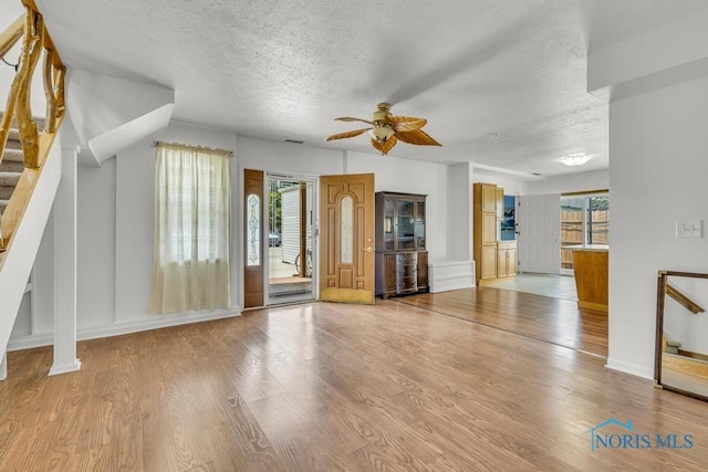 3133 126th St, Toledo, OH 43611 - unfurnished living room with a textured ceiling, stairway, a ceiling fan, and light wood-style flooring