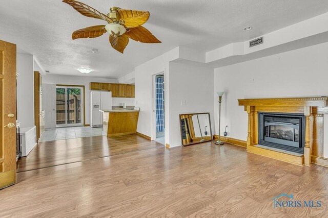 3133 126th St, Toledo, OH 43611 - unfurnished living room featuring a glass covered fireplace, light wood-style floors, and ceiling fan