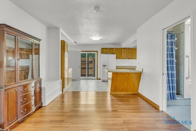 3133 126th St, Toledo, OH 43611 - kitchen with white fridge with ice dispenser, a peninsula, light wood-type flooring, brown cabinetry, and light countertops