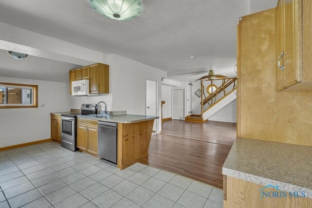 3133 126th St, Toledo, OH 43611 - kitchen featuring stainless steel appliances, light tile patterned flooring, light countertops, brown cabinets, and a textured ceiling