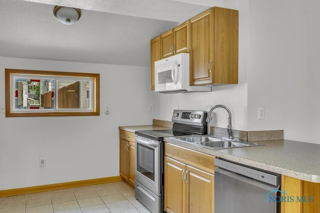 3133 126th St, Toledo, OH 43611 - kitchen featuring appliances with stainless steel finishes, light tile patterned floors, brown cabinetry, and light countertops