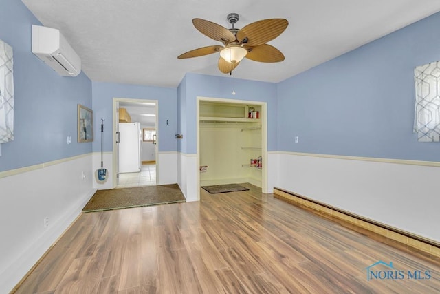 3133 126th St, Toledo, OH 43611 - unfurnished bedroom featuring a wall unit AC, wood finished floors, a ceiling fan, a closet, and freestanding refrigerator