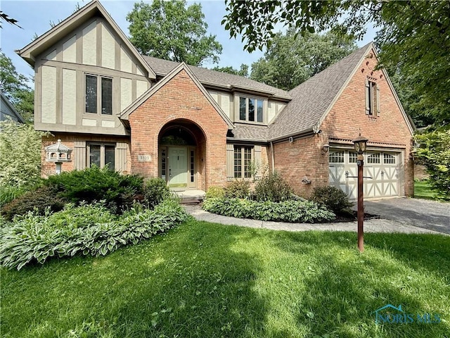 2325 Saint Roberts Ln, Toledo, OH 43617 - tudor-style house featuring brick siding, asphalt driveway, a front yard, a shingled roof, and stucco siding