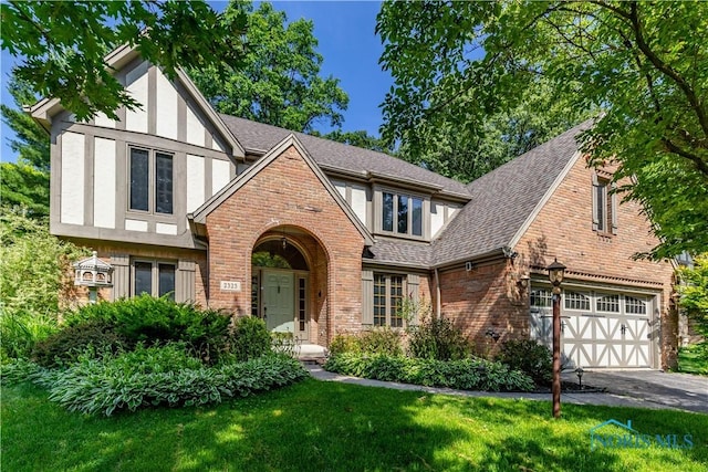 2325 Saint Roberts Ln, Toledo, OH 43617 - tudor-style house with brick siding, asphalt driveway, a front yard, and a garage