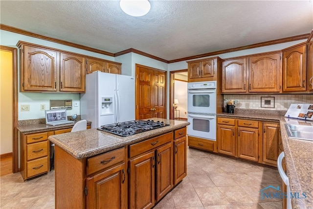 2325 Saint Roberts Ln, Toledo, OH 43617 - kitchen with white appliances, brown cabinetry, a center island, tasteful backsplash, and a textured ceiling