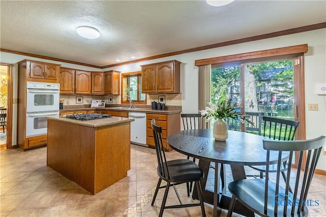 2325 Saint Roberts Ln, Toledo, OH 43617 - kitchen with white appliances, crown molding, a kitchen island, healthy amount of natural light, and brown cabinets