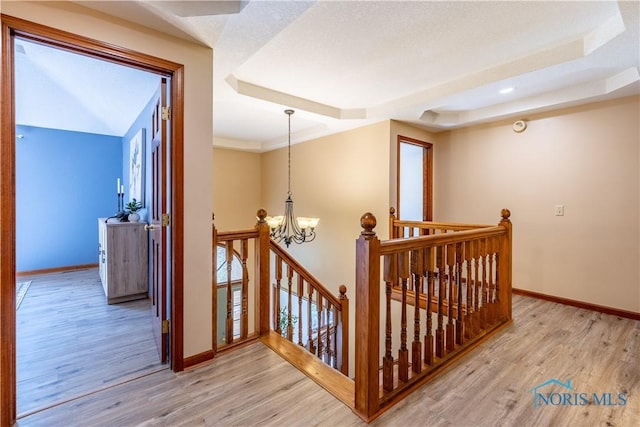 2325 Saint Roberts Ln, Toledo, OH 43617 - hallway featuring an upstairs landing, a chandelier, light wood-style flooring, and a tray ceiling