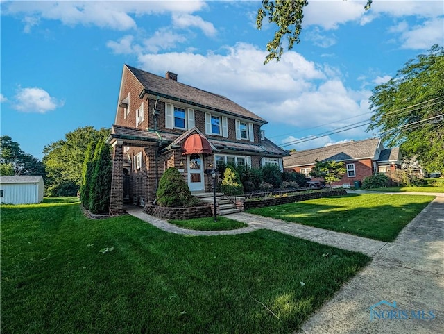 120 Elm St, Fostoria, OH 44830 - view of front of house featuring a front lawn, a chimney, and brick siding