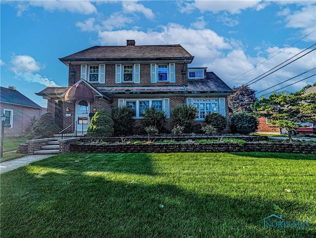 120 Elm St, Fostoria, OH 44830 - view of front of house featuring brick siding, a front lawn, and a chimney