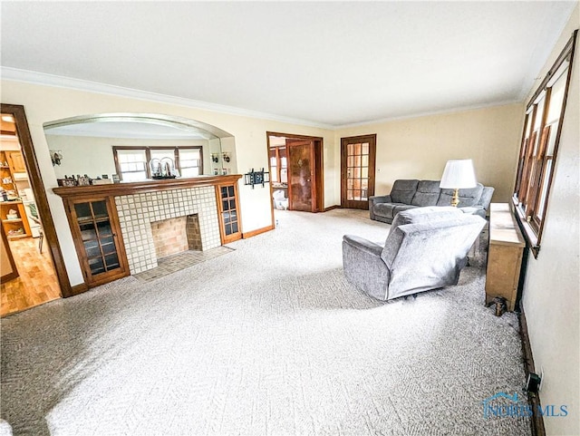 120 Elm St, Fostoria, OH 44830 - living room featuring ornamental molding, carpet, plenty of natural light, arched walkways, and a tiled fireplace
