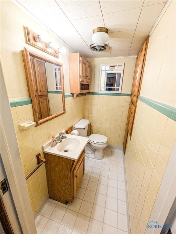 120 Elm St, Fostoria, OH 44830 - half bath featuring tile walls, tile patterned flooring, vanity, and a wainscoted wall