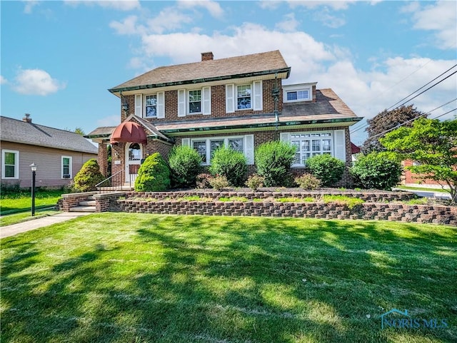 120 Elm St, Fostoria, OH 44830 - view of front facade featuring brick siding, a front yard, and a chimney