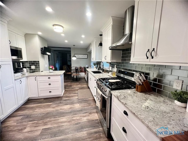 3822 Sylvan Wood Dr, Sylvania, OH 43560 - kitchen with wall chimney exhaust hood, stainless steel appliances, a peninsula, decorative backsplash, and white cabinets