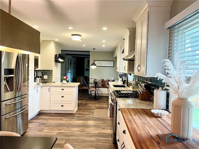 3822 Sylvan Wood Dr, Sylvania, OH 43560 - kitchen with appliances with stainless steel finishes, butcher block counters, a peninsula, dark wood-type flooring, and decorative backsplash