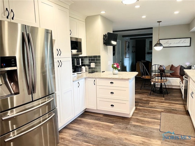 3822 Sylvan Wood Dr, Sylvania, OH 43560 - kitchen with appliances with stainless steel finishes, dark wood-style flooring, a peninsula, white cabinets, and decorative backsplash