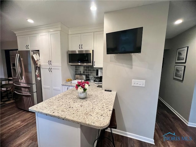 3822 Sylvan Wood Dr, Sylvania, OH 43560 - kitchen featuring appliances with stainless steel finishes, white cabinetry, dark wood-style floors, backsplash, and light stone countertops