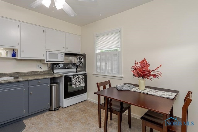 921 7th St, Maumee, OH 43537 - kitchen with white appliances, a ceiling fan, dark countertops, and white cabinets