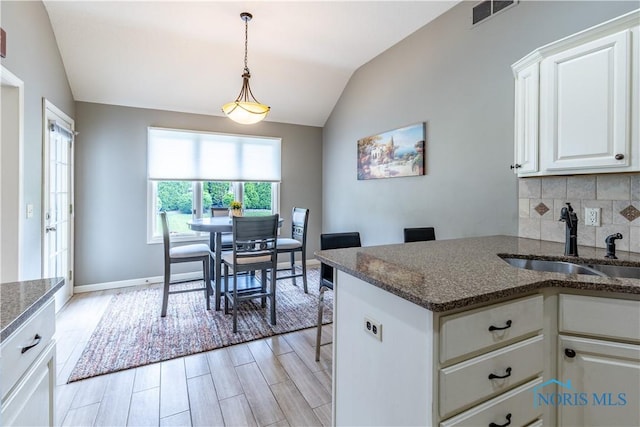 6666 Brick Yard Ct, Maumee, OH 43537 - kitchen with lofted ceiling, white cabinets, dark stone countertops, tasteful backsplash, and decorative light fixtures