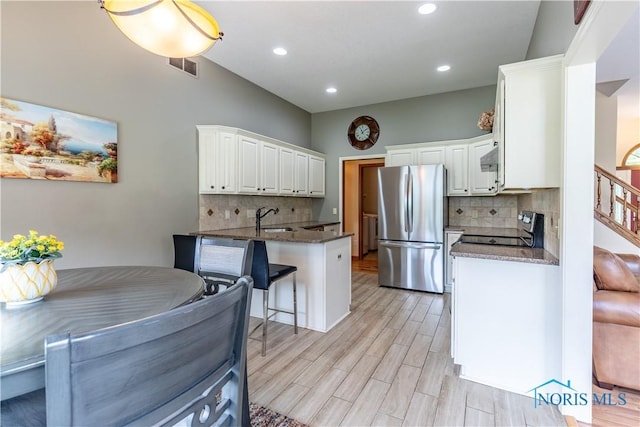 6666 Brick Yard Ct, Maumee, OH 43537 - kitchen with freestanding refrigerator, stove, a peninsula, white cabinets, and decorative backsplash
