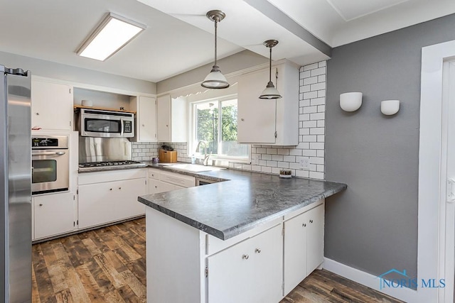 2338 Greenlawn Dr, Toledo, OH 43614 - kitchen featuring appliances with stainless steel finishes, a peninsula, backsplash, white cabinetry, and dark countertops
