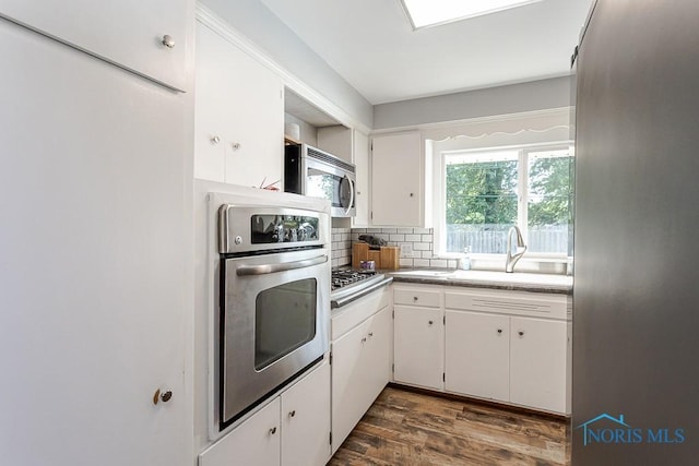 2338 Greenlawn Dr, Toledo, OH 43614 - kitchen with appliances with stainless steel finishes, white cabinets, decorative backsplash, and dark wood finished floors