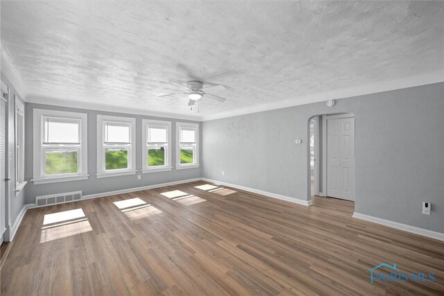 5542 N Summit St, Toledo, OH 43611 - unfurnished room with a textured ceiling, ceiling fan, wood finished floors, and arched walkways