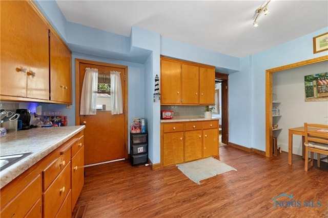 125 Cherry St, Wauseon, OH 43567 - kitchen featuring light countertops, dark wood-style flooring, tasteful backsplash, and brown cabinetry