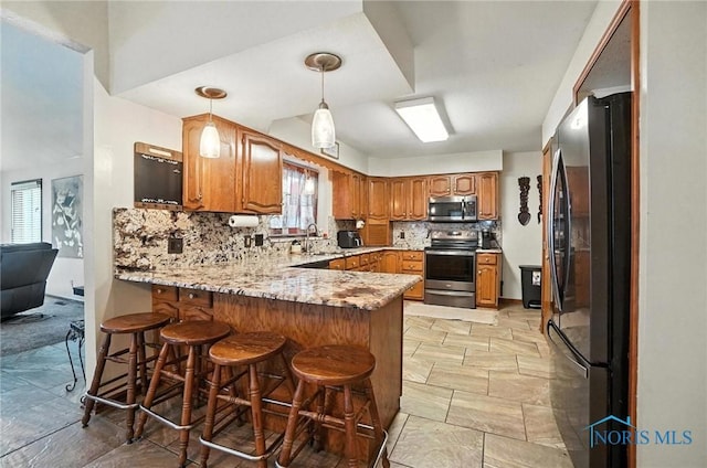 4871 Olde Meadow Ln, Sylvania, OH 43560 - kitchen featuring stainless steel appliances, a peninsula, decorative backsplash, brown cabinets, and hanging light fixtures