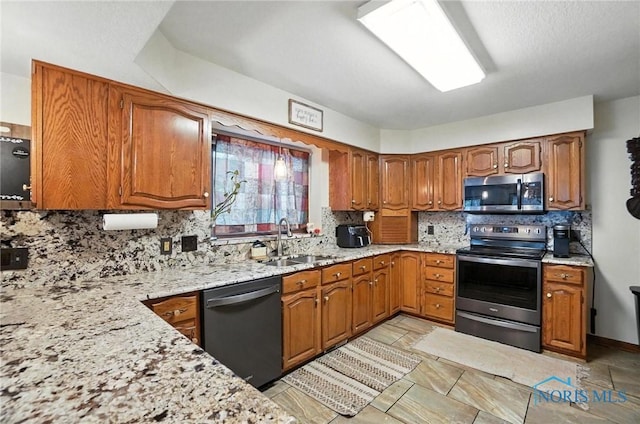 4871 Olde Meadow Ln, Sylvania, OH 43560 - kitchen featuring appliances with stainless steel finishes, brown cabinetry, tasteful backsplash, and light stone counters