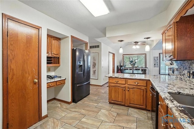 4871 Olde Meadow Ln, Sylvania, OH 43560 - kitchen with black fridge, a peninsula, brown cabinets, light stone counters, and ceiling fan