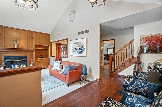 4871 Olde Meadow Ln, Sylvania, OH 43560 - living area featuring high vaulted ceiling, hardwood / wood-style flooring, a chandelier, stairway, and a glass covered fireplace