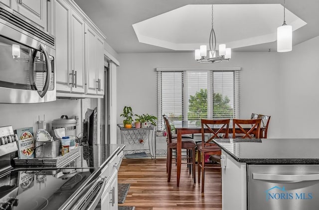 2923 Belle Glade Dr, Toledo, OH 43617 - kitchen with appliances with stainless steel finishes, a chandelier, dark wood-style floors, white cabinetry, and pendant lighting