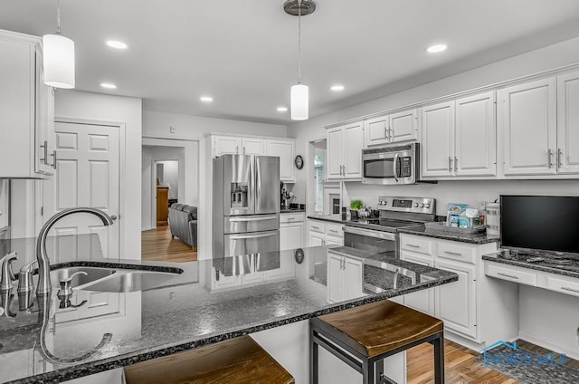 2923 Belle Glade Dr, Toledo, OH 43617 - kitchen with appliances with stainless steel finishes, white cabinetry, a kitchen bar, recessed lighting, and pendant lighting