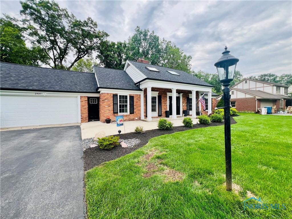 2921 Byrnwyck, Maumee, OH 43537 - neoclassical / greek revival house featuring brick siding, a front yard, a garage, and a shingled roof