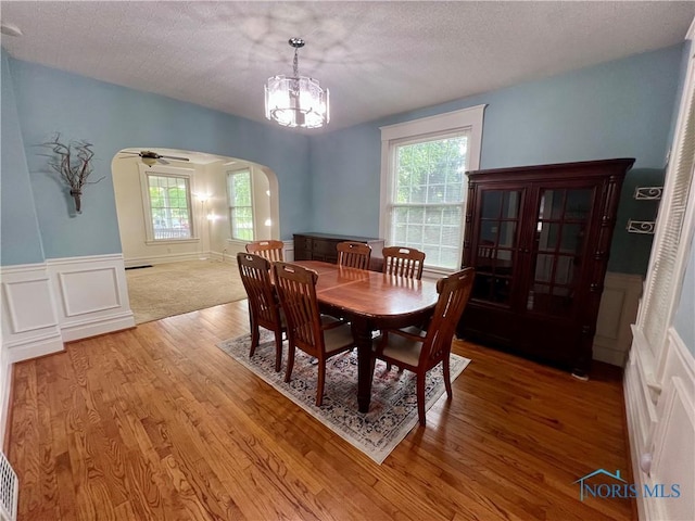 1810 E Broadway St, Toledo, OH 43605 - dining space with arched walkways, light wood-type flooring, a wainscoted wall, a chandelier, and a ceiling fan