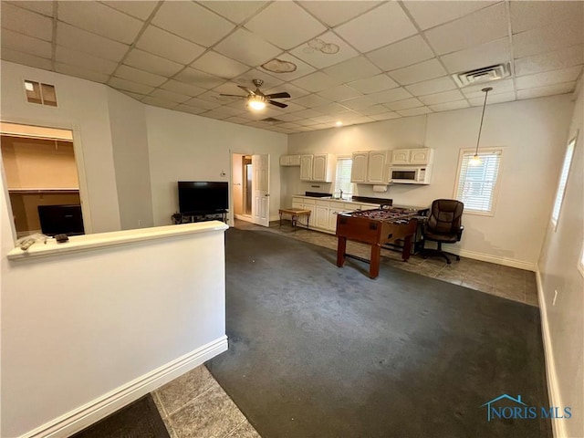 1810 E Broadway St, Toledo, OH 43605 - kitchen with white microwave, dark colored carpet, a drop ceiling, a ceiling fan, and decorative light fixtures