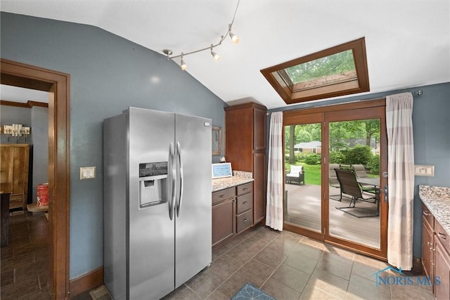 2617 Shetland Rd, Toledo, OH 43617 - kitchen with stainless steel fridge with ice dispenser, lofted ceiling, a skylight, and light stone counters