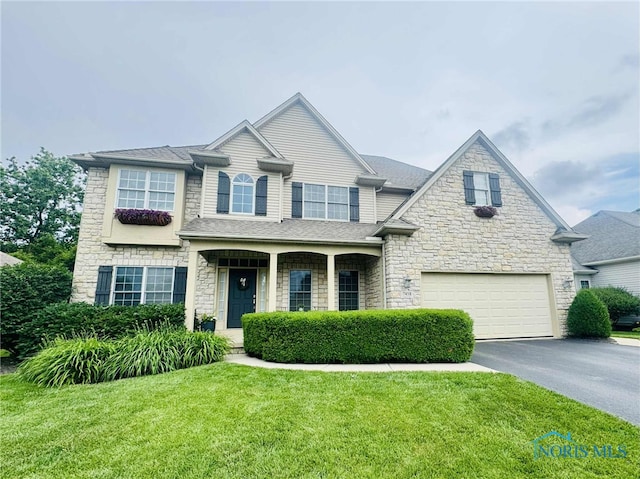 7458 Kaolin Rd, Maumee, OH 43537 - view of front facade featuring a garage, asphalt driveway, stone siding, and a front yard