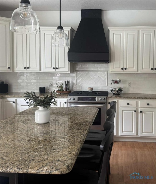 7458 Kaolin Rd, Maumee, OH 43537 - kitchen with custom range hood, stainless steel range with gas stovetop, white cabinetry, and decorative backsplash
