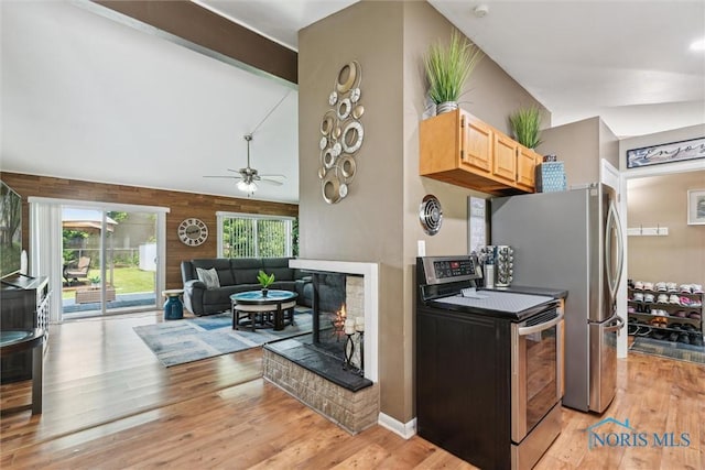3530 Devon Hill Rd, Toledo, OH 43606 - kitchen with stainless steel electric range oven, light wood-style floors, a ceiling fan, a multi sided fireplace, and wooden walls