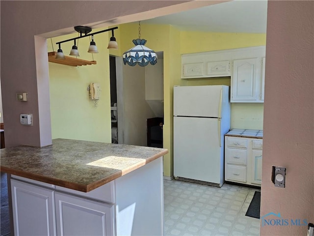 4745 Ottawa Trail Dr, Toledo, OH 43611 - kitchen featuring freestanding refrigerator, light flooring, white cabinetry, lofted ceiling, and pendant lighting