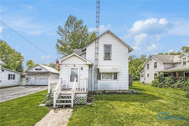 130 S 1st St, Hamler, OH 43524 - view of front facade with an outdoor structure, a detached garage, a front lawn, and asphalt driveway