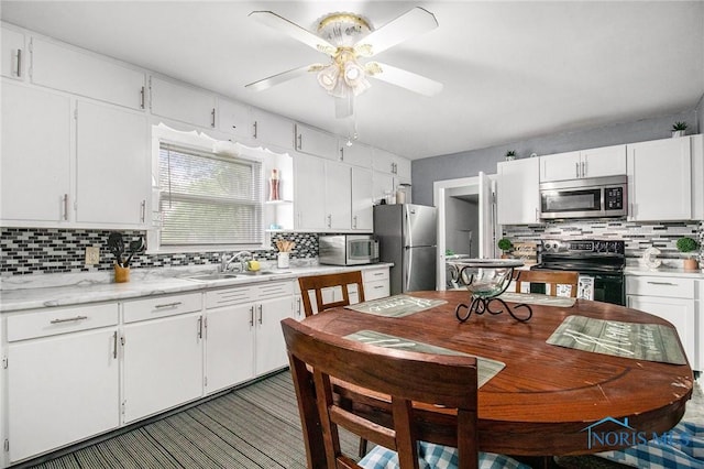 130 S 1st St, Hamler, OH 43524 - kitchen with appliances with stainless steel finishes, backsplash, light countertops, white cabinetry, and a ceiling fan