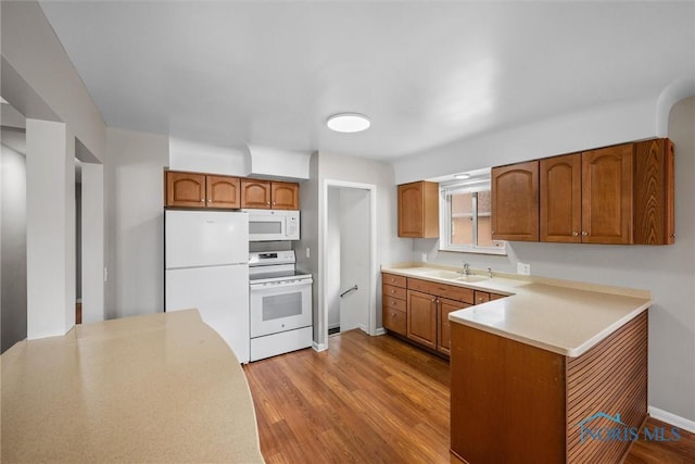 3431 146th St, Toledo, OH 43611 - kitchen featuring white appliances, brown cabinets, wood finished floors, a peninsula, and light countertops