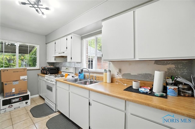 1732 Gilbert Rd, Toledo, OH 43614 - kitchen featuring white gas stove, under cabinet range hood, tasteful backsplash, white cabinetry, and light tile patterned flooring